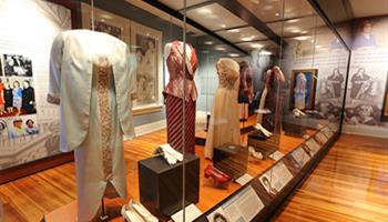 historic dresses in glass display cases in center of exhibit